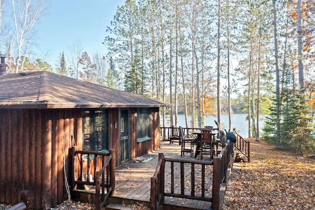 deck with a water view and outdoor dining area