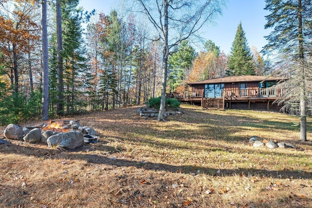 view of yard featuring a forest view and a wooden deck