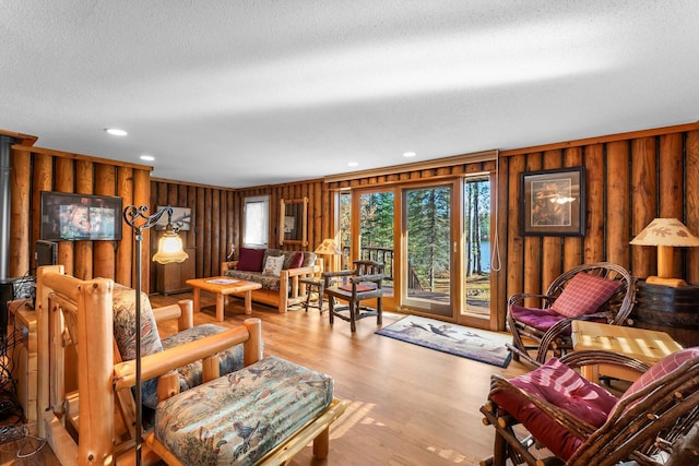 living room featuring recessed lighting, wooden walls, a textured ceiling, and wood finished floors