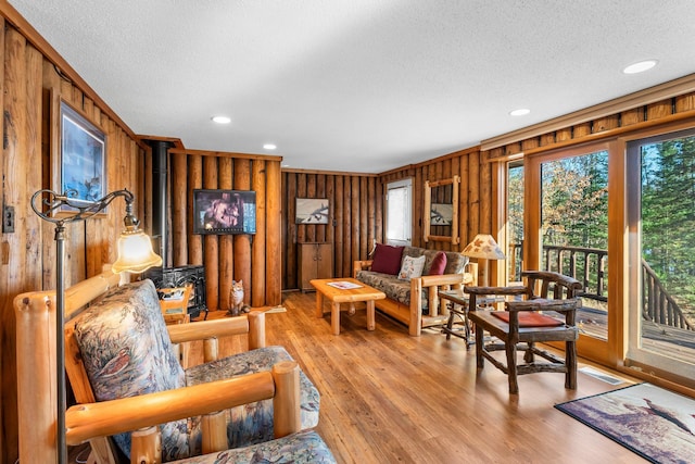 living room with a wood stove, a textured ceiling, wooden walls, and recessed lighting