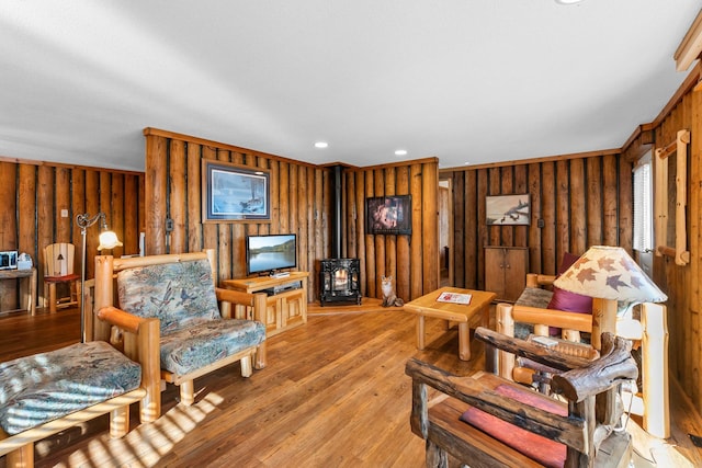living area with light wood-style flooring, a wood stove, wooden walls, and recessed lighting