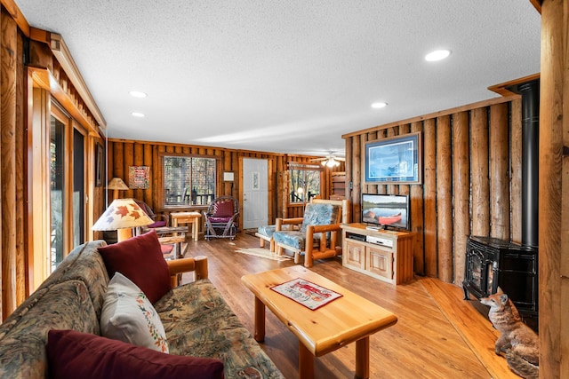 living area with light wood-style flooring, a wood stove, recessed lighting, and a textured ceiling