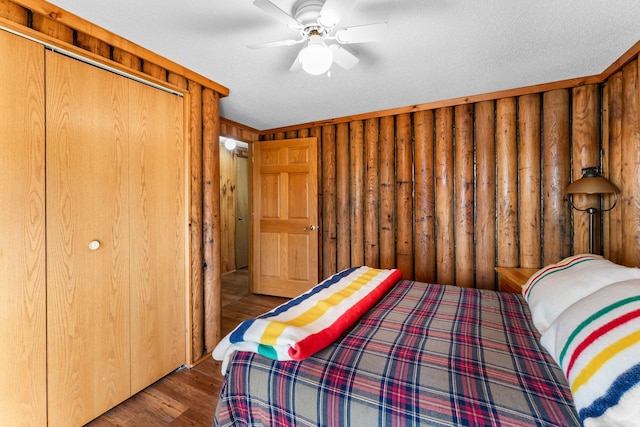 bedroom featuring wooden walls, ceiling fan, a closet, and wood finished floors