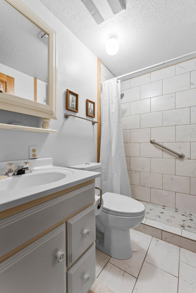 full bathroom with a tile shower, a textured ceiling, vanity, toilet, and marble finish floor