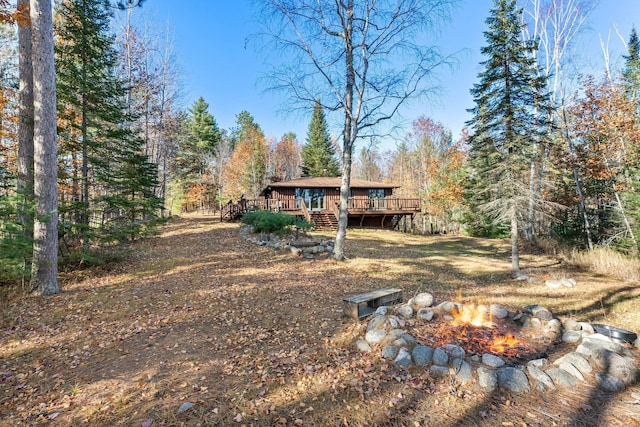 exterior space featuring a forest view, an outdoor fire pit, and a wooden deck