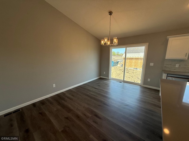 unfurnished dining area with a chandelier, baseboards, dark wood-style flooring, a glass covered fireplace, and vaulted ceiling