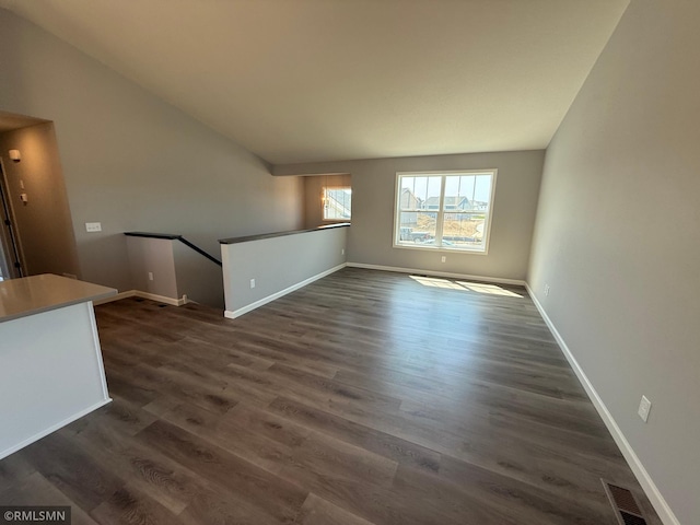 unfurnished living room with dark wood-type flooring and baseboards