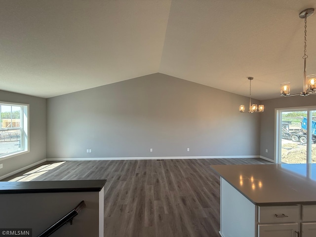 unfurnished dining area with a chandelier, dark wood-type flooring, baseboards, and vaulted ceiling