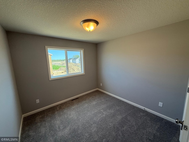 empty room featuring dark colored carpet, baseboards, and a textured ceiling