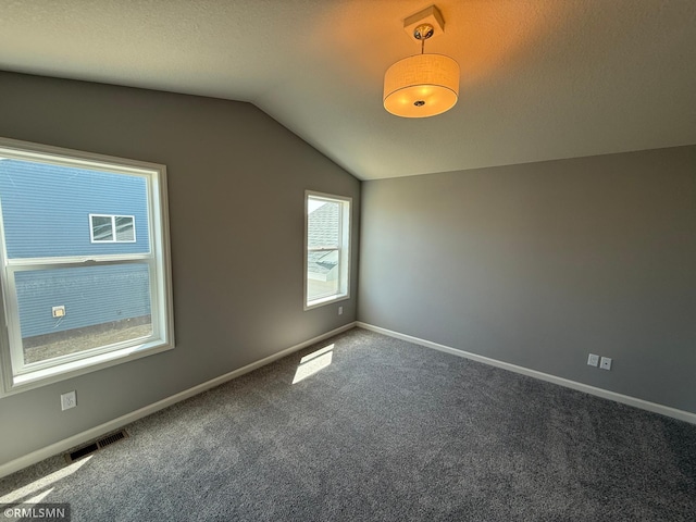 unfurnished room featuring lofted ceiling, carpet floors, and baseboards
