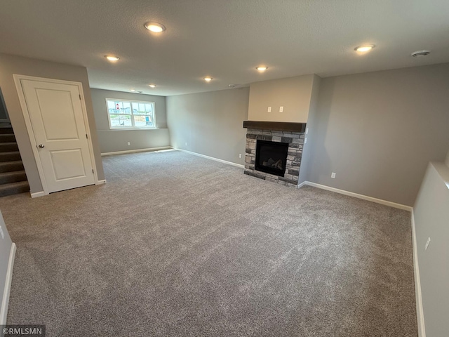 unfurnished living room featuring carpet flooring, baseboards, a fireplace, stairway, and recessed lighting
