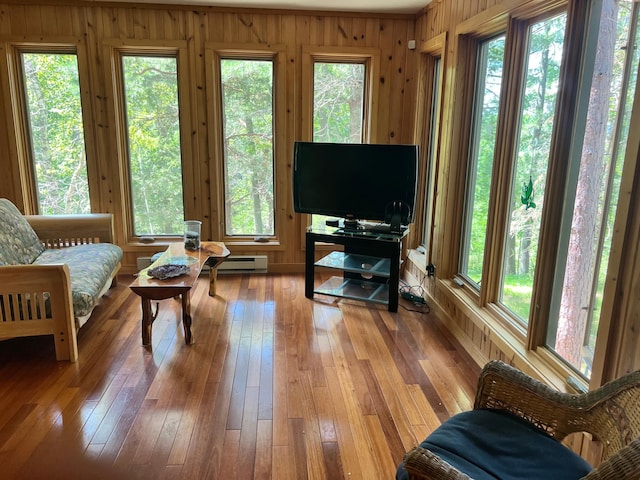 living area with a baseboard radiator, wooden walls, and light wood-type flooring