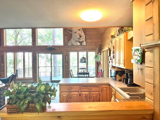 kitchen featuring light brown cabinetry, light countertops, a peninsula, and a textured ceiling