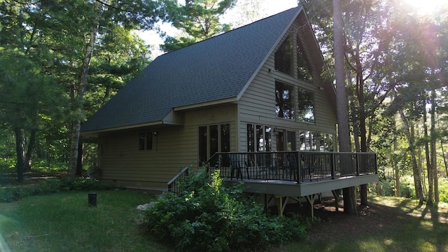 back of house featuring roof with shingles and a deck