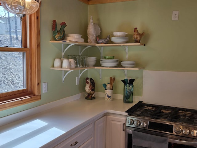 details with a notable chandelier, light countertops, white cabinetry, open shelves, and gas range