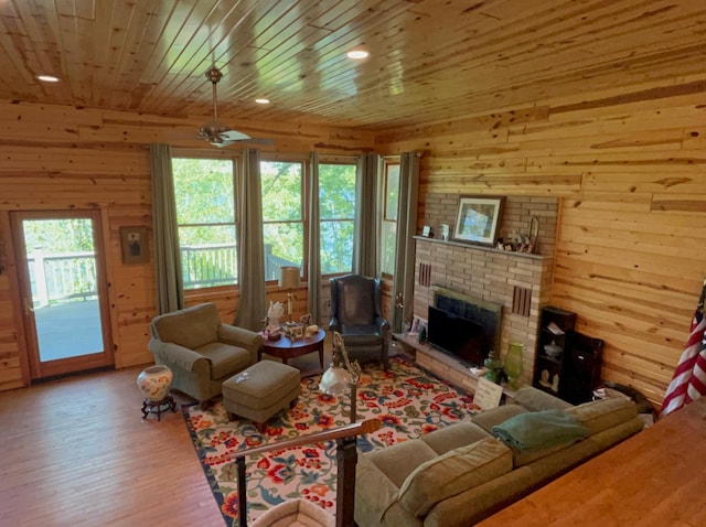 living area with wooden walls, wood finished floors, wooden ceiling, and a brick fireplace