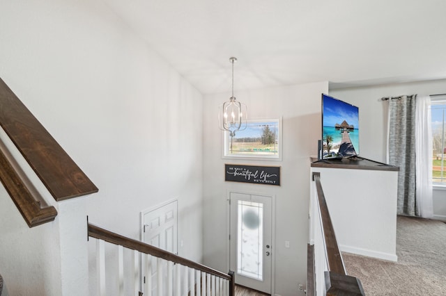 foyer entrance with stairway, carpet flooring, baseboards, and a notable chandelier