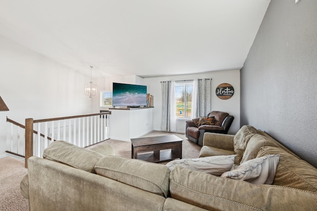 carpeted living area with baseboards and a notable chandelier