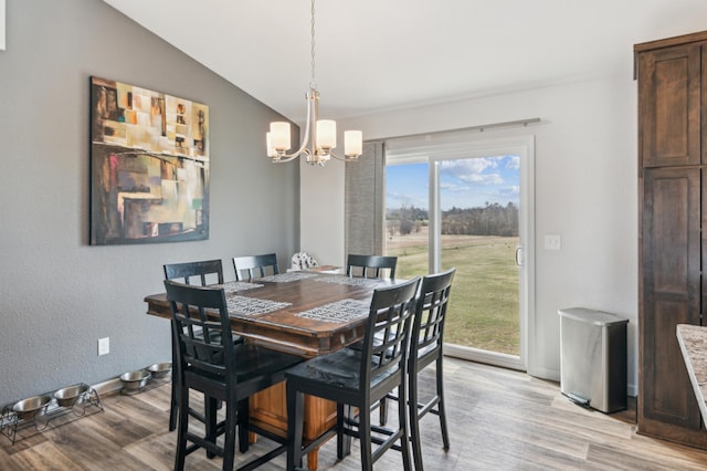 dining room with vaulted ceiling, light wood-style flooring, baseboards, and a notable chandelier