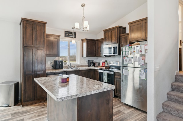 kitchen with lofted ceiling, a sink, light wood-style floors, and appliances with stainless steel finishes