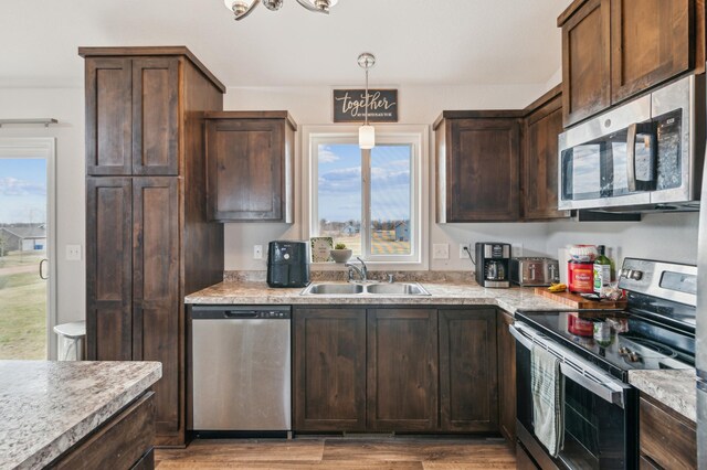 kitchen featuring light countertops, appliances with stainless steel finishes, dark brown cabinetry, and a sink