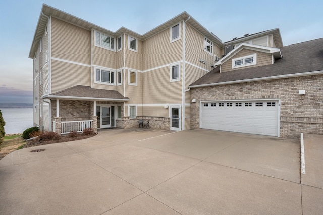 200 Michigan St Unit 1, Lake City, MN 55041 - back of property featuring roof with shingles, a porch, concrete driveway, brick siding, and a garage