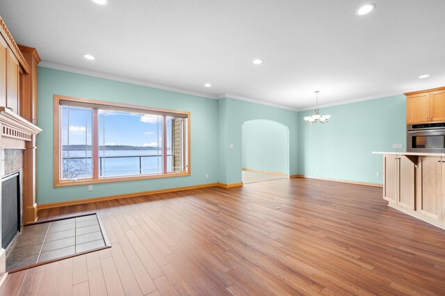 200 Michigan St Unit 1, Lake City, MN 55041 - unfurnished living room featuring recessed lighting, arched walkways, a premium fireplace, light wood-type flooring, and a chandelier