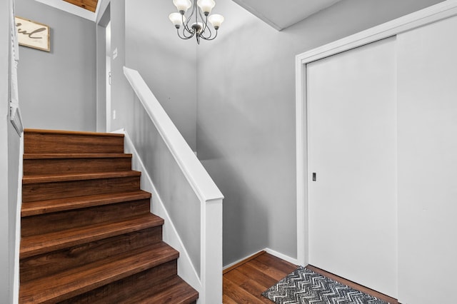 staircase featuring wood finished floors and a chandelier