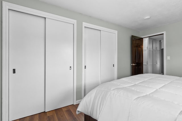 bedroom featuring multiple closets and dark wood-style flooring