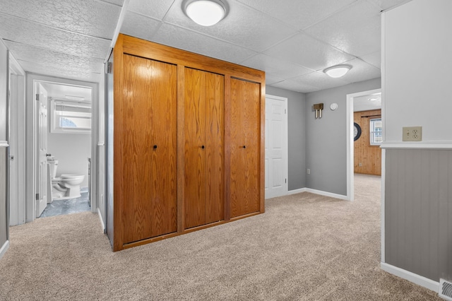 unfurnished bedroom featuring carpet flooring, a drop ceiling, and baseboards