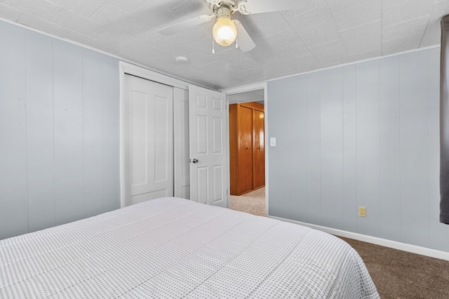 bedroom featuring carpet, ceiling fan, a closet, baseboards, and a decorative wall