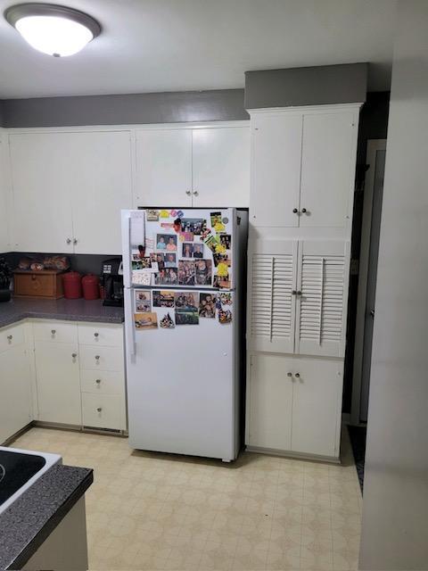 106 Mcphail Ave N, Caledonia, MN 55921 - kitchen featuring freestanding refrigerator, light flooring, and white cabinets