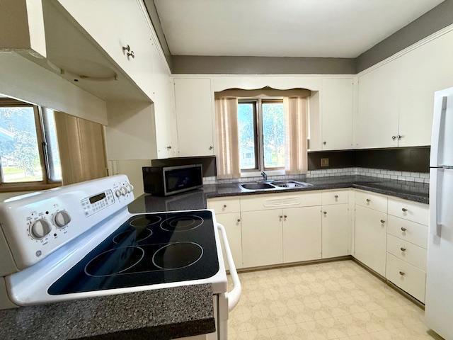 106 Mcphail Ave N, Caledonia, MN 55921 - kitchen with white appliances, dark countertops, white cabinets, and exhaust hood