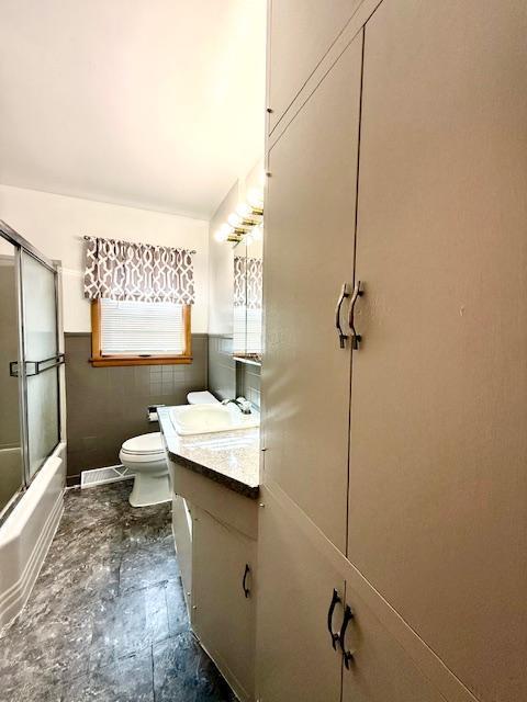106 Mcphail Ave N, Caledonia, MN 55921 - bathroom with vanity, a wainscoted wall, enclosed tub / shower combo, and tile walls