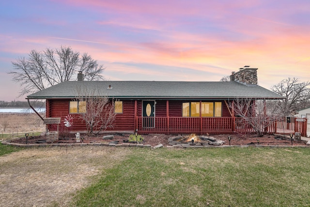 view of front of house with a front yard, log exterior, a shingled roof, and a chimney