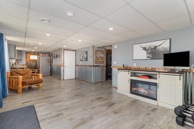 living area with recessed lighting, light wood-style flooring, and a drop ceiling