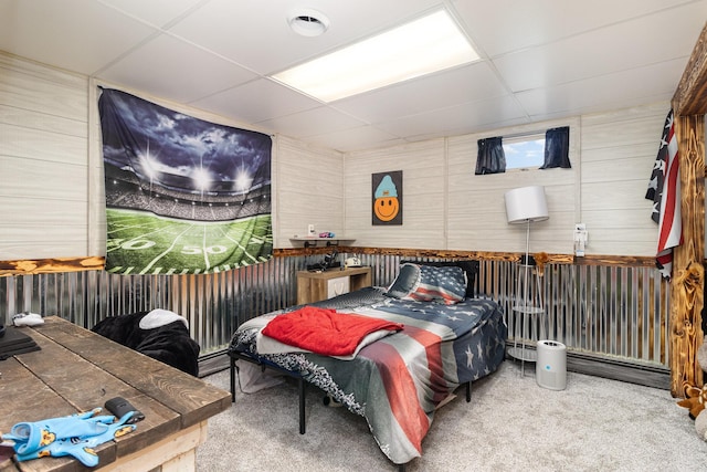 bedroom featuring wooden walls, a paneled ceiling, and carpet flooring
