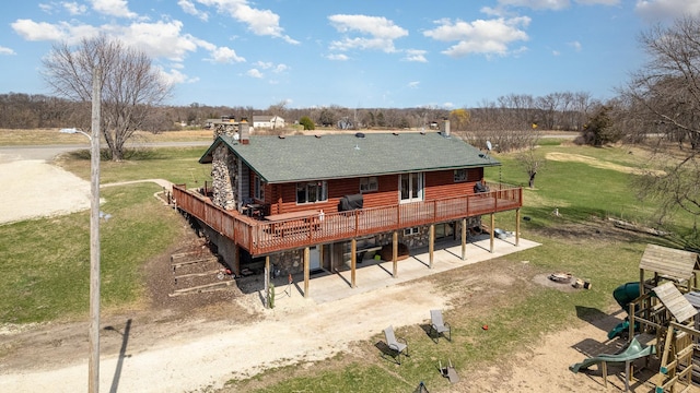 rear view of property featuring a patio area, a lawn, a deck, log siding, and a shingled roof