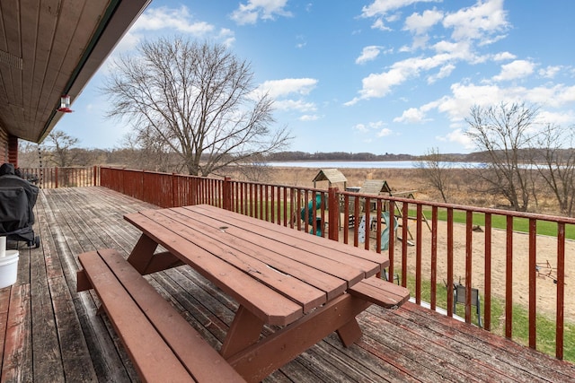 deck featuring a playground, outdoor dining area, and a water view