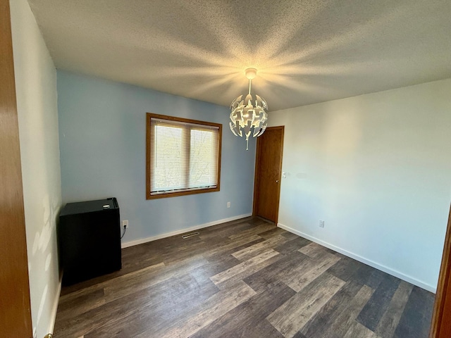 14303 Utica Ave, Savage, MN 55378 - spare room with a chandelier, dark wood finished floors, baseboards, and a textured ceiling