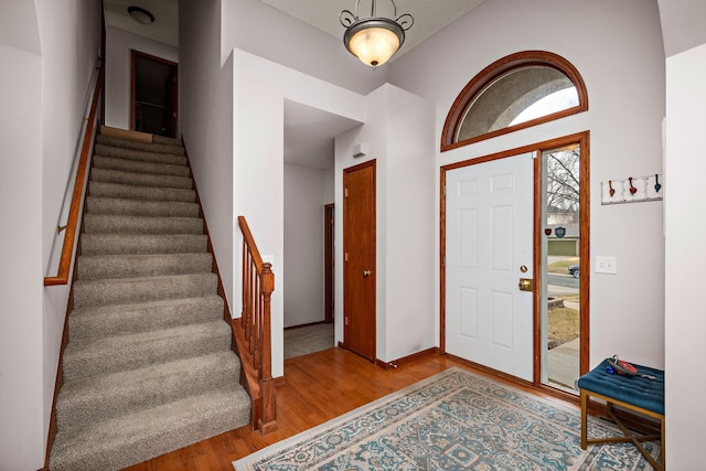 foyer featuring baseboards, stairway, and wood finished floors