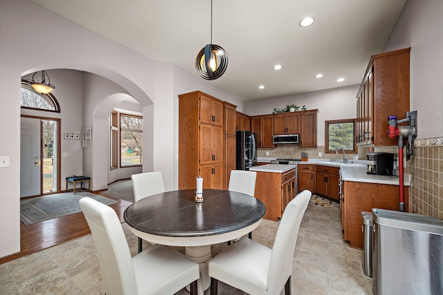 kitchen with stainless steel microwave, plenty of natural light, light countertops, and refrigerator with ice dispenser