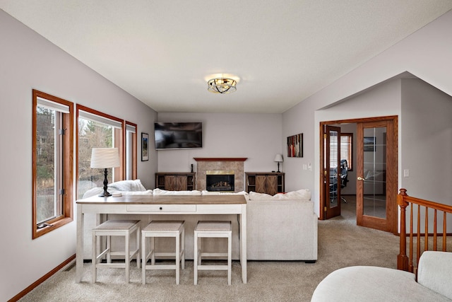 carpeted living area featuring french doors, baseboards, a glass covered fireplace, and visible vents