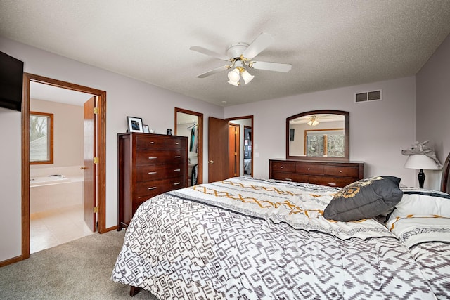 bedroom with a closet, a spacious closet, ensuite bathroom, carpet floors, and visible vents