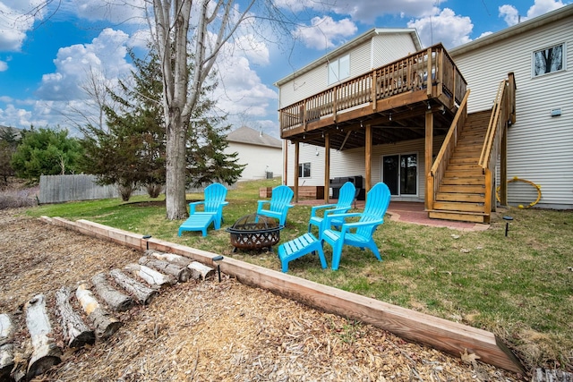 back of property with an outdoor fire pit, a lawn, fence, stairs, and a wooden deck