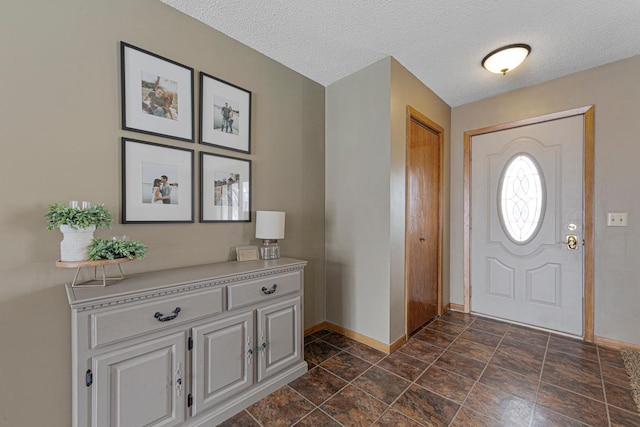 foyer entrance with a textured ceiling and baseboards