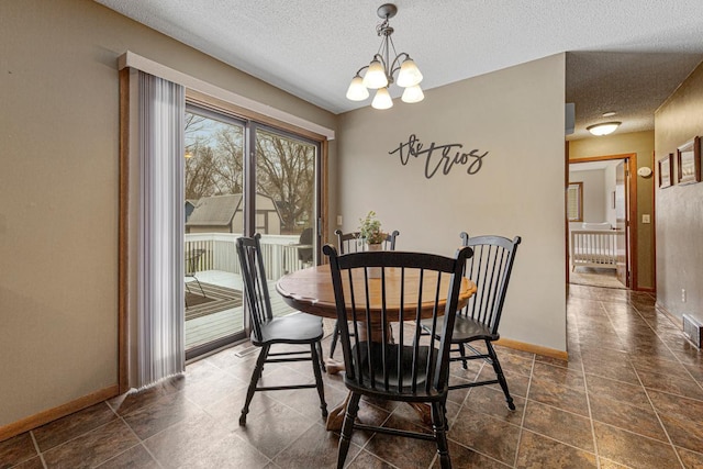 dining room featuring a chandelier, a textured ceiling, and baseboards