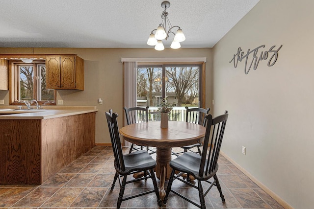dining space featuring a chandelier, a textured ceiling, a healthy amount of sunlight, and baseboards