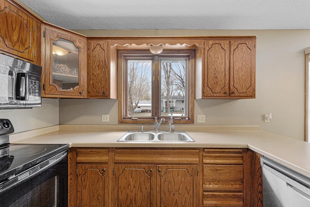 kitchen with black appliances, brown cabinets, a sink, and light countertops
