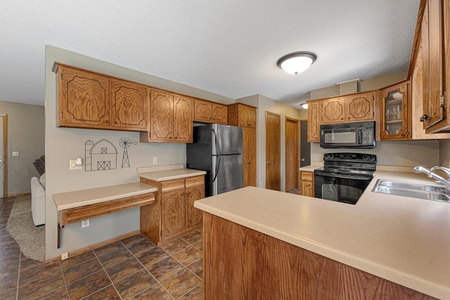 kitchen featuring black appliances, brown cabinets, and a sink
